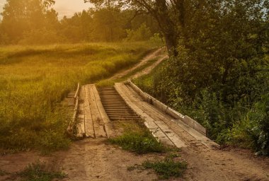 Batan güneşin ışınlarında dere üzerinde ahşap köprü