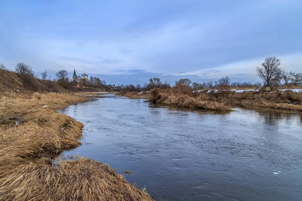 Der Fluss ist Spätherbst unter dunklem Himmel, Ufer mit trockenem Gras — Stockfoto