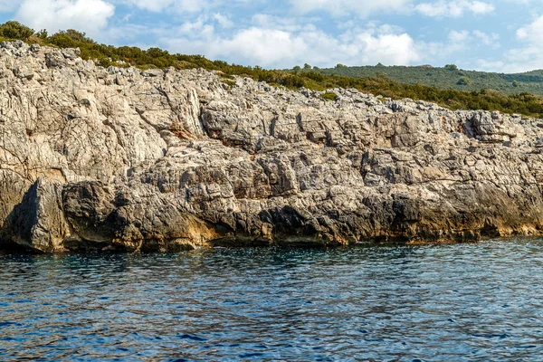 Rocky seashore, limestone cliffs covered with vegetation on a summer sunny day — Stock Photo, Image