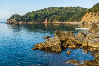 Karadağ'da budva kasabası yakınlarında sabahın erken saatlerinde deniz kıyısı, deniz suyu ve taşlar