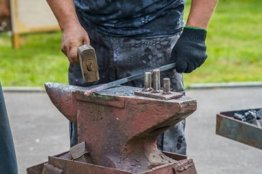 demirci kırmızı-sıcak metal iş parçası eziyor 