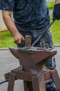 demirci kırmızı-sıcak metal iş parçası eziyor 