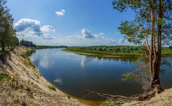 Высокий крутой берег реки, покрытый лесом, с видом на реку и хребет. — стоковое фото