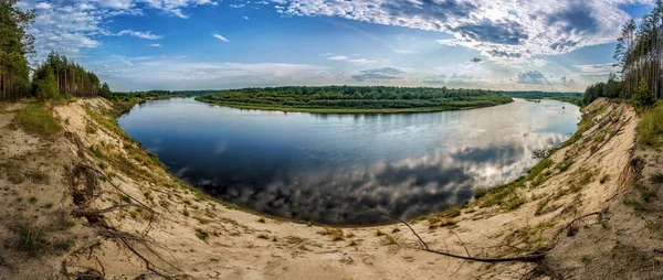 Річка і поле на заході сонця під високою піщаною скелею — стокове фото