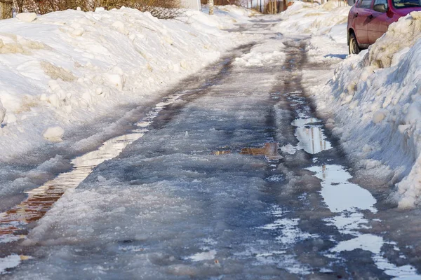 Schnee- und eisbedeckte Winterstraße mit Pfützen und Spurrillen — Stockfoto