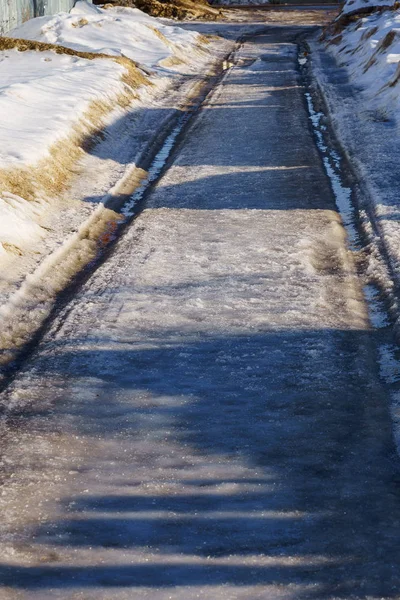 Vinterväg täckt med snö och is med pölar och innanmäte — Stockfoto