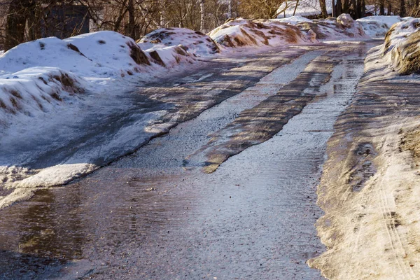 Vinterväg täckt med snö och is med pölar och innanmäte — Stockfoto