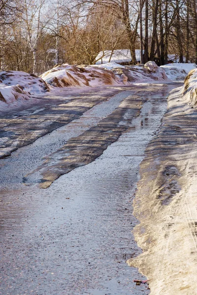 Schnee- und eisbedeckte Winterstraße mit Pfützen und Spurrillen — Stockfoto