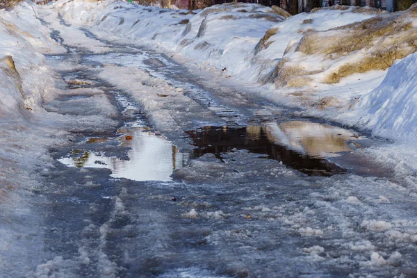 Vinterväg täckt med snö och is med pölar och innanmäte — Stockfoto