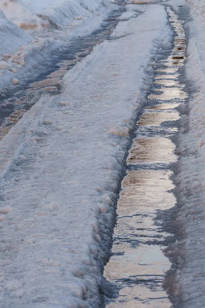 Vinterväg täckt med snö och is med pölar och innanmäte — Stockfoto