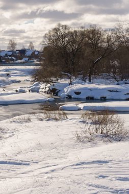 Güneşli bir kış gününde nehir kısmen buzla kaplı.