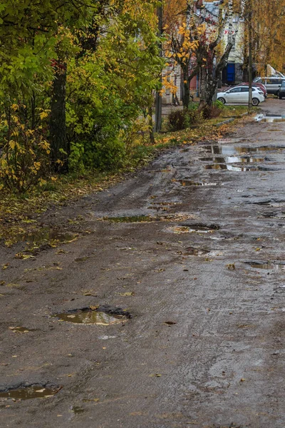 Droga w prowincjonalnym rosyjskim mieście w złym stanie, doły i brud — Zdjęcie stockowe