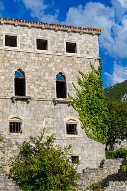 Ortaçağ kalesinde pencereleri olan taş bir binanın ön cephesi 