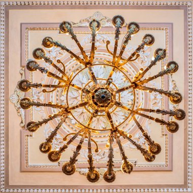 Kültür Merkezi 'nin koridorunda alçıyla süslenmiş tavanın altında parlak bir avize var.