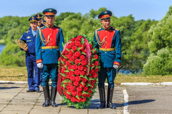 Vojáci v plných šatech držet věnec z červených květin — Stock fotografie