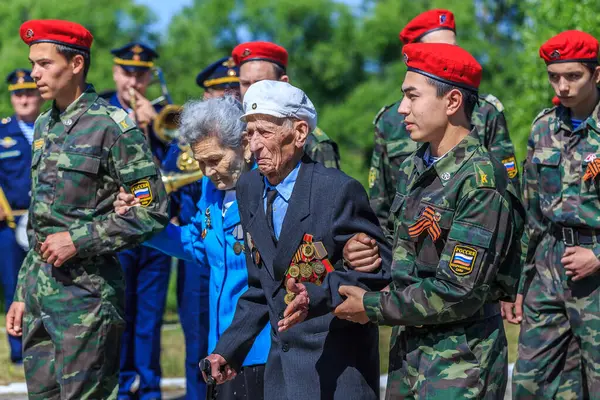 Soldaten helpen ouderen op de achtergrond van groene bomen — Stockfoto