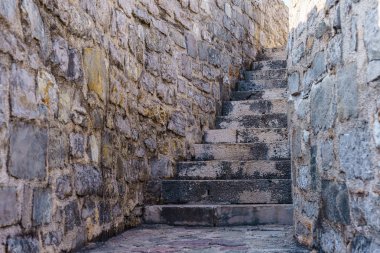 Eski bir kalenin içinde çitleri olan taş bir merdiven..