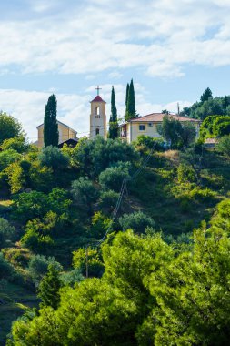 Yeşilliklerle çevrili bir binanın yakınındaki tepede.