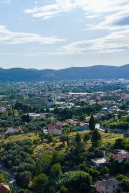 Dağların arkasında, kiremitlerle döşenmiş tavanlar ve yeşillikler...