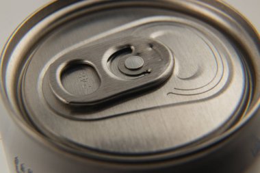 A metallic beverage can top is shown in detail, highlighting the pull tab and the smooth surface. Perfect for illustrating modern packaging design and functionality.