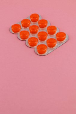 Parlak turuncu tabletler pembe arka planda gümüş bir tepside düzenlenir. Canlı renklerini ve hatta boşluklarını gösterir..