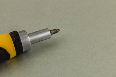 Lviv Ukraine 05.22.25 A close-up view showing the tip of a yellow and silver screwdriver against a neutral gray background, highlighting the details of the tool's head.