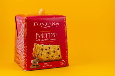 Ukraine Lviv 20.08.25A red packaged panettone with chocolate chips sits against a bright yellow background, showcasing its festive design. Perfect for holiday celebrations or gifts.