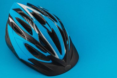 Lviv Ukraine 05.22.25 A vibrant blue and black cycling helmet sits on a smooth blue surface, highlighting its sleek design and safety features perfect for outdoor biking adventures.