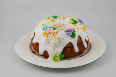 A round cake featuring white icing draped over the top, adorned with vibrant flowers and decorative elements, perfect for a festive occasion or celebration.
