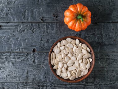 Siyah ahşap bir masa üzerinde kabak çekirdeği ile kil kase. Vejetaryen mutfağı. Üstten Görünüm.