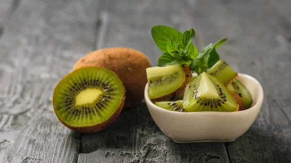 Kiwi salad and mint and kiwi fruit on a wooden table. Tropical vegetarian dish.