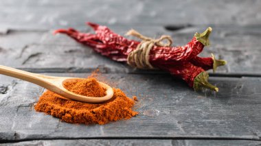 Koyu ahşap bir masada kırmızı biberli ahşap bir kaşık. Tüm yemekler için evrensel baharat.