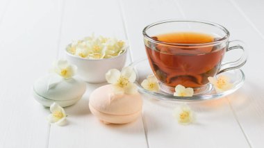 Hatmi macaroons çay ve bir beyaz tahta masaya Yasemin çiçek. Bahar çay kompozisyon beyaz bir tablo.
