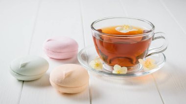 Taze çay ve bir beyaz tahta masada üç renkli şekerleme hazırlanmış. Sabah kahvaltı bileşimi. Bahar çay kompozisyon beyaz bir tablo.