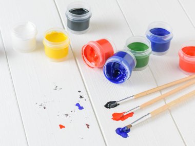 Guaj ve üç çok renkli fırçalar bir ahşap masa kavanoz üzerinde dağınık. Yaratıcı kiti. Hobi ve stil.