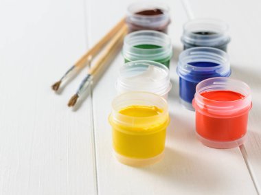 Guaj ve fırçalar bir beyaz tahta masada açık kavanoz... Yaratıcı kiti. Hobi ve stil.