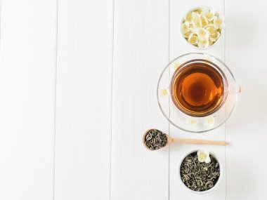 Yasemin ve beyaz bir masaya çiçek bir kase bitkisel çay. Sabah kahvaltı bileşimi. Bahar çay kompozisyon beyaz bir tablo. Düz yatıyordu.