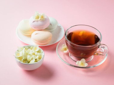 Taze çay ve pembe bir tablo üzerinde renkli şekerleme hazırlanmış. Sabah kahvaltı bileşimi. Bahar çay kompozisyon beyaz bir tablo.