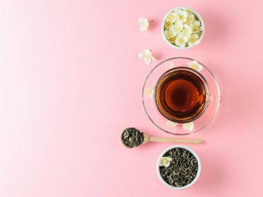 Yasemin ve pembe bir masaya çiçek bir kase bitkisel çay. Sabah kahvaltı bileşimi. Bahar çay kompozisyon beyaz bir tablo. Düz yatıyordu.