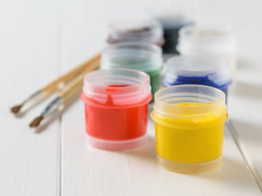 Guaj ve fırçalar bir beyaz tahta masada açık kavanoz... Yaratıcı kiti. Hobi ve stil.