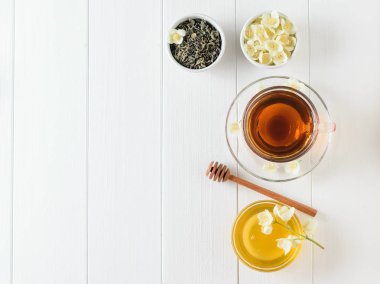 Yasemin ve beyaz bir masaya çiçek bir kase bitkisel çay. Sabah kahvaltı bileşimi. Bahar çay kompozisyon beyaz bir tablo. Düz yatıyordu.