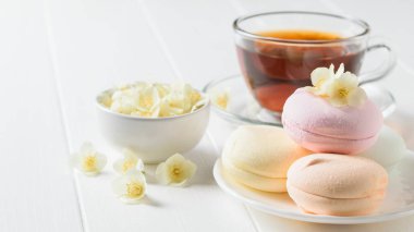 Taze çay ve bir beyaz tahta masada üç renkli şekerleme hazırlanmış. Sabah kahvaltı bileşimi. Bahar çay kompozisyon beyaz bir tablo.