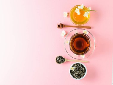 Bitkisel çay, bal, Yasemin çiçekleri ve bir tahta kaşık pembe bir tablo. Sabah kahvaltı bileşimi. Bahar çay kompozisyon beyaz bir tablo. Düz yatıyordu. Üstten görünüm.