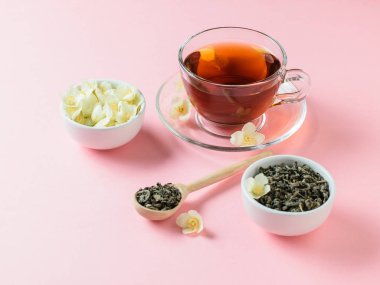 Bitkisel çay, bal, Yasemin çiçekleri ve bir tahta kaşık pembe bir tablo. Sabah kahvaltı bileşimi. Bahar çay kompozisyon beyaz bir tablo. Pastel renk.