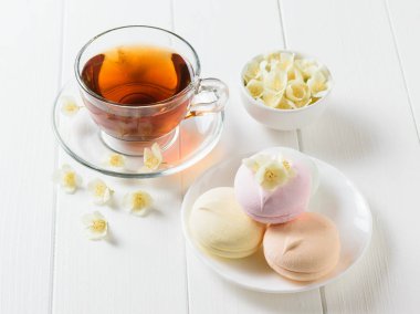 Taze çay ve bir beyaz tahta masada üç renkli şekerleme hazırlanmış. Sabah kahvaltı bileşimi. Bahar çay kompozisyon beyaz bir tablo.