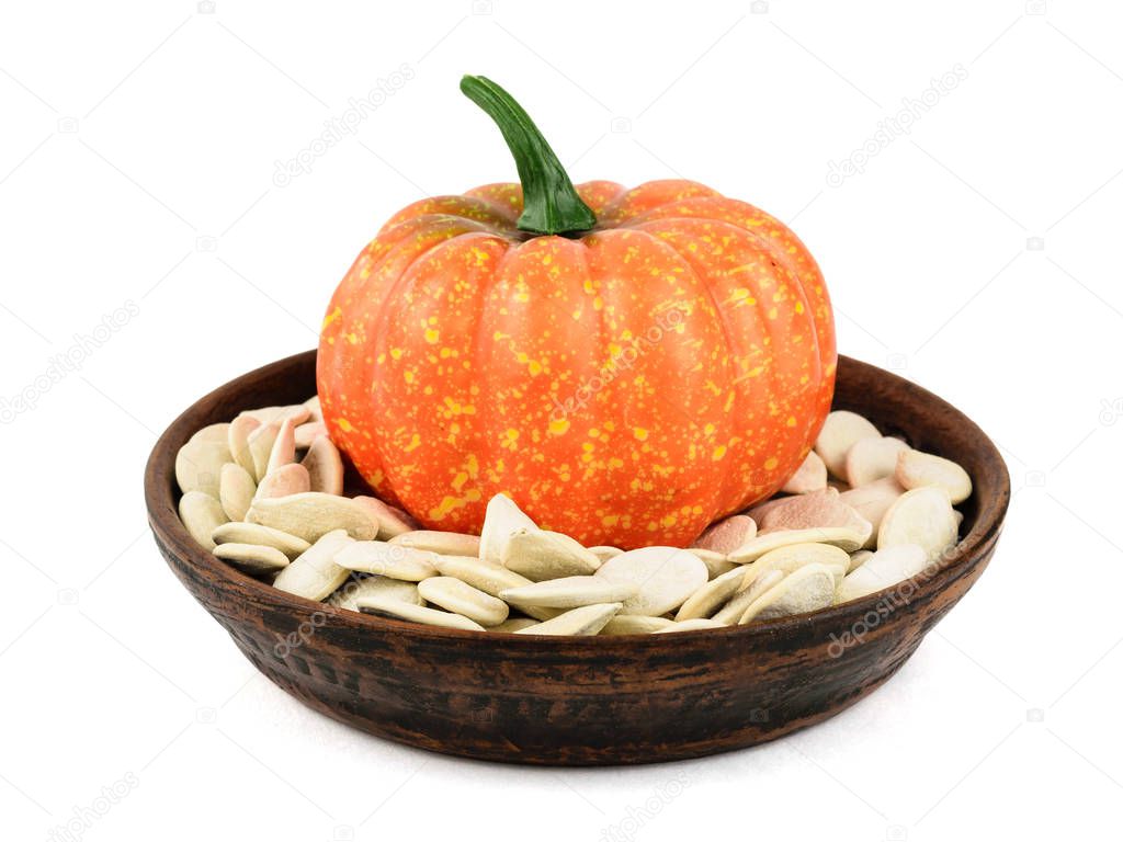 Decorative pumpkin with seeds in a clay bowl isolated on a white background. Decoration for Halloween.