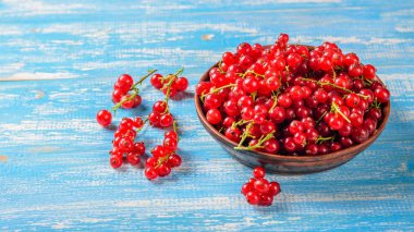 Mavi ahşap bir masa üzerinde bir kil kase taze çekilmiş somun çilek. Sağlıklı doğal gıda kavramı.