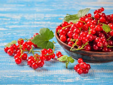 Mavi ahşap bir masa üzerinde bir kil kase taze çekilmiş somun çilek. Sağlıklı doğal gıda kavramı.