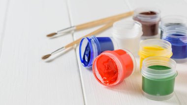Guaj ve fırçalar bir beyaz tahta masada açık kavanoz... Yaratıcı kiti. Hobi ve stil.