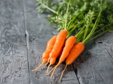 Taze havuç koyu ahşap bir masa üzerinde bir grup. Vejetaryen gıda ham doğal ürünlerle kavramı.